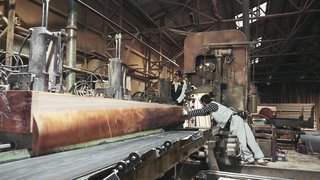 Long beams are prepared by workers in a Yoshino factory, ready to be taken and used at the building site.
