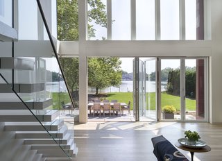 The new extension opens out dramatically onto the rear yard, which faces the river. The living space expands beyond indoors and flows outside to an outdoor deck with a large dining table.
