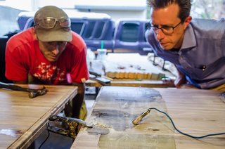 Designer James Davis had been experimenting with electrical erosion for about six months before meeting Vertical Arts' Brian Patty at a networking event. They quickly devised a plan to incorporate the technique into a multi-purpose table for VA's new office space. Using a solution of baking soda and saltwater to provide a general pattern, electrical clamps run through a series of microwave transformers to create a unique design on walnut butcher block. 