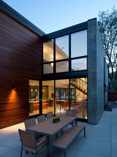 The back patio becomes another dining room when a full wall of doors open from the kitchen/dining area. In warm months, the couples' young son pushes his Strider Bike between the spaces. "He could do laps around the whole house if he wanted to," said his dad. Cedar siding brings warmth to the concrete patio and board-formed, concrete accent wall. 