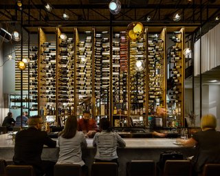 The two story wine rack at Il Posto serves as a focal point within the space. It also functions as a screen between diners and the kitchen. Guests are afforded multiple views of the towering piece as the stair to the mezzanine slides behind the rack and moves through the space. 