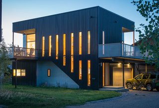 CACHE CREEK – With constraints arising from issues of budget, footprint, and a densely populated neighborhood, this project took the form of a simple, inverted two-story box. The upper level features the master bedroom, living area, and kitchen, as well as decks and windows that connect to views of nearby ski slopes. The lower level contains two guest bedrooms, garage, and utility area. Inside, high ceilings and generous glazing emphasize daylight, while the exterior is clad in black corrugated metal and galvanized steel-clad projections. The structure’s height allows for roof access and even a climbing wall on the north elevation. Photos by Audrey Hall.