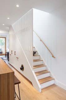 CAB Architects deftly hid appliances, pantry storage, and a litter box for the owners' two cats in the cabinetry beneath this staircase in Ritchie Rowhouse.
