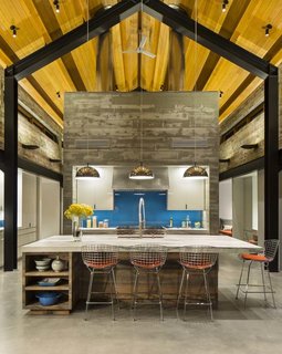 The cathedral-shaped steel beams outline the open plan of the main house, which includes a kitchen, upstairs loft, bathrooms, and hallways that connect all of the yurt structures. The central structure is made of concrete and serves as a thermal mass to keep the home cool in summer and warm in winter.