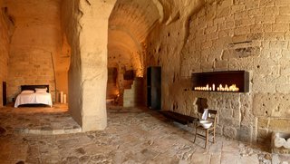 Ever Wanted to Stay in a Cave That’s Actually Pretty Modern Inside? - Photo 10 of 10 - Located in the UNESCO World Heritage cave village of Sassi de Matera in Southern Italy, the rooms at Sextantio Le Grotto Della Civita are furnished with rustic pieces so that the textures and medieval vibes of the cave shines through.