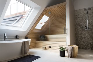 This converted attic in a turn-of-the-century building in Berlin’s Charlottenburg neighborhood has a large skylight on the side-slope of the roof, which allows one to look up at the sky while having a relaxing soak.
