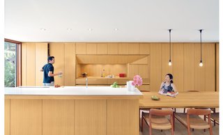 The sleek, storage-packed "kitchen-studio" in this minimalist Japanese-inspired home in Toronto is wrapped floor-to-ceiling with custom rift-cut white oak cabinetry to ensure clutter-free living.