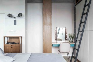 1930s modernism reigns in this studio flat, where a cabinet is used to separate the open-plan living, sleeping, and storage zones. Carefully selected loose furnishings, such as a denim-upholstered sofa by Stephen Kenn and a midcentury chest by Charlotte Perriand, expand the scale of the interior, making it feel roomier than its actual size.