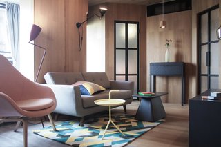 A colorful printed rug and matching cushion, a pink armchair, and plenty of bold geometric shapes give this apartment a slick, urban vibe.