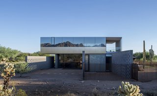 Szu-Ping Patricia Chen Suchart and Thamarit Suchart of Chen + Suchart Studio used brushed-stainless steel and glass on the upper volume of this Sonoran Desert home. The glass, which was treated with a thermal coating, provides protection from the sun and creates a surface with a silvery, mirrored effect that captures the colors of the desert and mountain peaks.