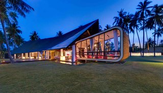 Designed by Canadian architect David Lombardi and set along an almost deserted beach in Lombok, this five-bedroom modern architectural gem has a torch-lined timber pathway and a guesthouse built into a manmade, grass-covered hill. 