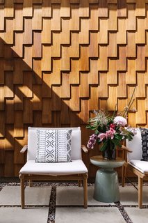This home in northeast Austin, Texas, has a back patio with floors made out of concrete and stone and walls of wood shingles.