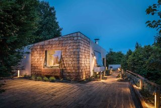 Inspired by bird hides, this annex building in Cornwall, England, that was part of an existing thatch cottage was fully revamped with concrete and silver-wood shingles to create a minimalist rental cottage.