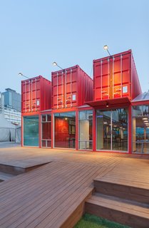 Discover 5 Public Buildings in South Korea Made Out of Shipping Containers - Photo 5 of 10 - Bold, red-colored shipping containers were used to create a 39-foot-long extension for visitors to the National Theatre Company of Korea. Designed as a social zone for theatergoers, the space was equipped with internal sliding partition walls that can be opened or closed to allow for flexible use of the interior spaces. 