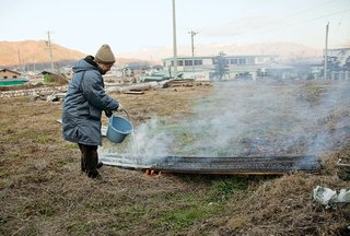 Japanese architect Terunobu Fujimori pours water to cool the boards.