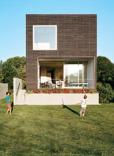 This Rhode Island home is composed of a a modernist box structure with an exterior of milled, charred, brushed, and oiled cypress slats manufactured by Delta Millworks.