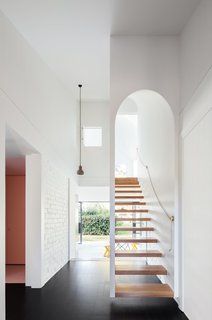 Designed by TRIBE Studio Architects, this renovated Arts and Crafts family home in Sydney’s leafy North Shore has an arched main entrance at the front of the house and a narrow floating staircase with a threshold that mimics the facade's arch.