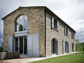 Marrying an industrial color scheme with a splash of country charm, this vacation villa designed by Rob Landeweerd in Tuscany manages to harmonize its old and segmented arched doors with a contemporary interior.