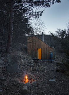 As a wilderness retreat for a songwriter, this compact, prefabricated wooden hut in Wienerwald, Austria, was designed by architects Heike Schlauch and Robert Fabach of Austrian studio raumhochrosen architekturkonzepte. They sought to create a visual and geographical connection with the woods outside. The hut's asymmetrical roof, which slopes steeply on one side, gives it a distinctly modern visage amidst a rural setting.
