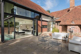 A 15th-century Tudor vacation rental in Kent, England, gets a modern update with glazing and polished steel, plus a large, sun-filled patio that's furnished with contemporary outdoor furniture.