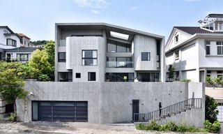 25 Modern Homes That Kill it With Concrete - Photo 15 of 25 - An undulating, S-shaped interior wall guides the programs within this Brutalist-inspired concrete abode. In the city of Hsinchu in northern Taiwan, Taipei-based firm Yuan Architects designed a four-level dwelling with a Brutalist-style, raw concrete shell. An S-shaped wall weaves through the interiors, carving up public and private spaces shared by three generations of a family. 