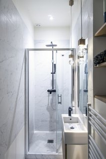 On one side of the cube, black doors that meld with the wall open to reveal an efficient wardrobe and a surprisingly bright marble bedroom.