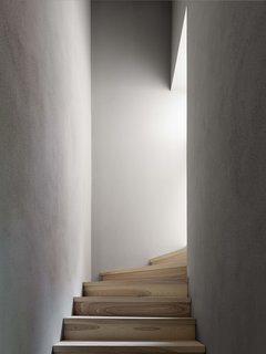 A small staircase winds between two narrow walls and up towards the attic.