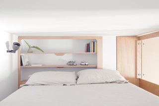The cabin-like bedroom contains a king-size bed and minimalist, built-in shelves.