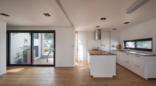 These 30 White Kitchens Are Anything But Ordinary - Photo 21 of 30 - Along the Southern side of the passageway is a living room, dining area, and kitchen, along with a workspace and guest bathroom. The door next to the kitchen opens to a striking courtyard. 