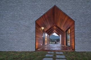 Fitted on all sides with warm wood, this double-height, gable-shaped passageway serves as the entrance to the house.