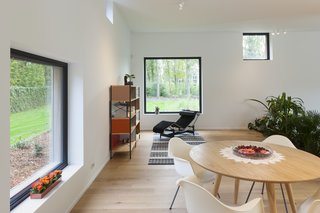 A black Arne Jacobsen Series 07 chair from Fritz Hansen is arranged with an Eames storage shelf from Vitra and white Eames DAX plastic armchairs.