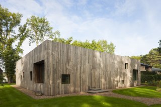 Several square perforations of varied sizes along the wooden facade serve as windows.