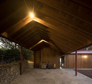 A Bright Red Island Residence Embraces a Linden Tree - Photo 4 of 13 - A wide, open-air, stone-paved corridor with a saltbox roof shelter