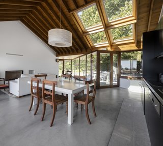 A Bright Red Island Residence Embraces a Linden Tree - Photo 8 of 13 - A simple, open-plan living, dining, and kitchen area feels connected with the outdoor courtyard.