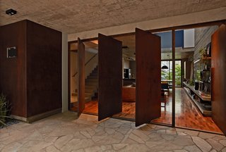 This Slender Concrete Home in Brazil Feels Like an Urban Jungle - Photo 3 of 13 - Four pivoting Cor-Ten steel doors help with cross ventilation.