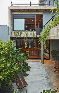This Slender Concrete Home in Brazil Feels Like an Urban Jungle - Photo 2 of 13 - The backyard garden has an outdoor grilling station.