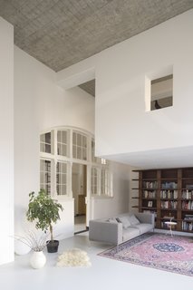 A 20th-Century Dutch Schoolhouse Now Holds a Series of Airy Lofts - Photo 4 of 13 - Behind the wooden bookshelf in the living lounge is a hidden staircase that leads up to the workspace.