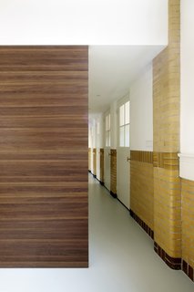A 20th-Century Dutch Schoolhouse Now Holds a Series of Airy Lofts - Photo 8 of 13 - A wooden box, which houses a walk-in closet and stairs to the bedrooms, acts as a partition that dissects the hallway.