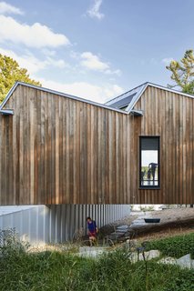 A stone foot path and a custom-made undercroft swing bench were incorporated into the pocket of space between the ground and the floor of the upper volume.