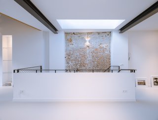 A 19th-Century Dutch Workshop Is Now a Stunning, Spacious Loft - Photo 7 of 13 - A versatile hallway on the upper level illustrates the harmonious blend of modern updates alongside the historic brick walls.
