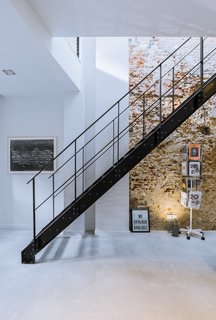 A 19th-Century Dutch Workshop Is Now a Stunning, Spacious Loft - Photo 5 of 13 - Exposed brick walls work with a black steel staircase and polished concrete floors to give the interior an edgy and modern atmosphere.