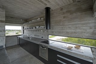 This Stacked Concrete Home Is Not Your Typical Golf Course Dwelling - Photo 9 of 17 - A streamlined kitchen houses a concrete slab countertop.