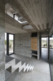This Stacked Concrete Home Is Not Your Typical Golf Course Dwelling - Photo 14 of 17 - Exposed concrete is used for the rail-less stairs.