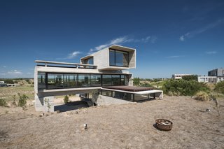 This Stacked Concrete Home Is Not Your Typical Golf Course Dwelling - Photo 1 of 17 - The middle volume is the largest and most transparent of the three stacked sections.