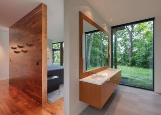 The bathroom has a large window that frames tree views.