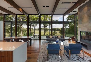 The house is sited on a wooded plateau overlooking a wetland and lake beyond.