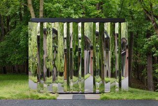 The shed's mirrored surface reflects delightfully distorted images of the natural surroundings.