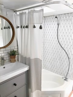 A renovated bathroom with a new showerstall and tiled wall.