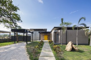 A Concrete Abode Becomes a Surfer's Paradise - Photo 1 of 23 - A bright yellow door serves as the main entrance to the vacation home.