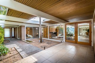 The living room feeds into a courtyard with a water feature.
